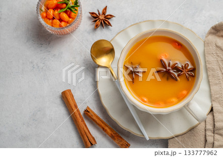 Sea buckthorn herbal tea in a cup on a light background with spices and berries. Sea buckthorn herbal tea in a cup on a light background with spices and berries. 133777962