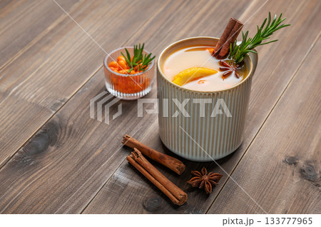 Sea buckthorn herbal tea in a cup on a wooden background with spices and berries. Sea buckthorn herbal tea in a cup on a wooden background with spices and berries. 133777965