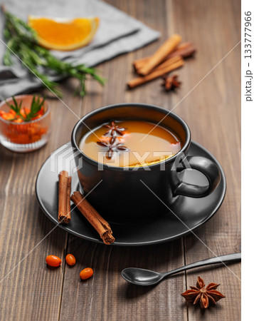 Sea buckthorn herbal tea in a black cup on a wooden background with spices Sea buckthorn herbal tea in a black cup on a wooden background with spices 133777966