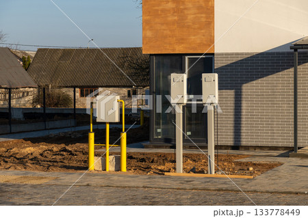 Exterior view of a newly built house with outdoor utility meters and yellow gas pipes installed Exterior view of a newly built house with outdoor utility meters and yellow gas pipes installed 133778449