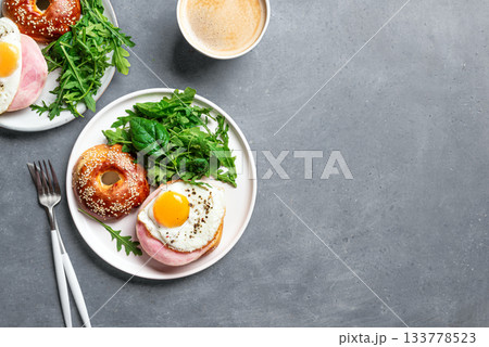 Healthy breakfast. Bagel sandwich with fried egg, ham and greens 133778523