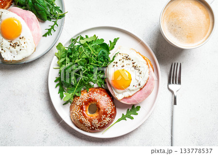 Healthy breakfast. Bagels with fried egg, ham and greens 133778537