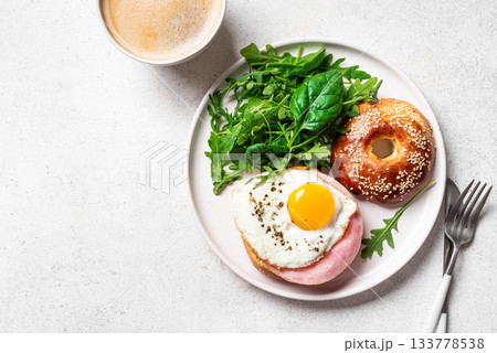 Healthy breakfast. Bagel with fried egg, ham and greens Healthy breakfast. Bagel with fried egg, ham and greens 133778538