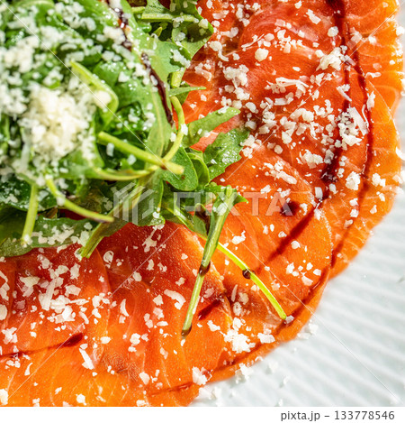 salmon carpaccio topped with fresh arugula, grated cheese and balsamic glaze, showcasing rich texture restaurant menu, culinary branding salmon carpaccio topped with fresh arugula, grated cheese and balsamic glaze, showcasing rich texture restaurant menu, culinary branding 133778546