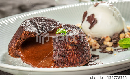 Warm chocolate lava cake with a rich molten center served with vanilla ice cream, nuts and chocolate flakes, gourmet dessert menu, branding and premium food 133778553