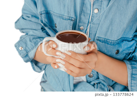 Woman in a denim shirt holding a warm cup of coffee in both hands, isolated on white background, perfect for morning coffee concepts, beverage advertising and comfortable home moments Woman in a denim shirt holding a warm cup of coffee in both hands, isolated on white background, perfect for morning coffee concepts, beverage advertising and comfortable home moments 133778624