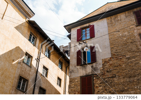 Bergamo's charming architecture with red shutters and aged facades under a blue sky. 133779064