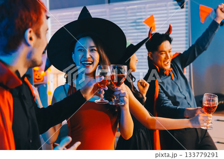 Joyful office Halloween party with coworkers in costumes, celebrating with drinks and laughter, fostering teamwork and festive spirit 133779291