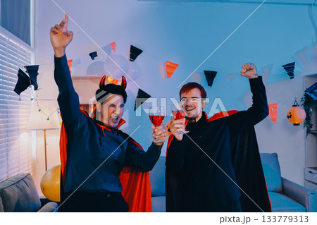 Joyful office Halloween party with coworkers in costumes, celebrating with drinks and laughter, fostering teamwork and festive spirit 133779313