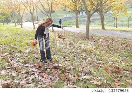 Woman collecting autumn leaves in park during autumn season Woman collecting autumn leaves in park during autumn season 133779628