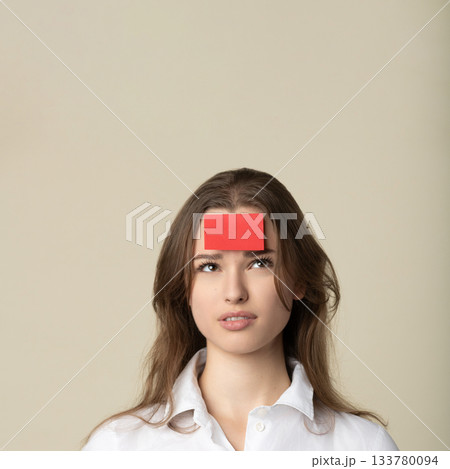 Woman with red sticker note on her forehead Woman with red sticker note on her forehead 133780094