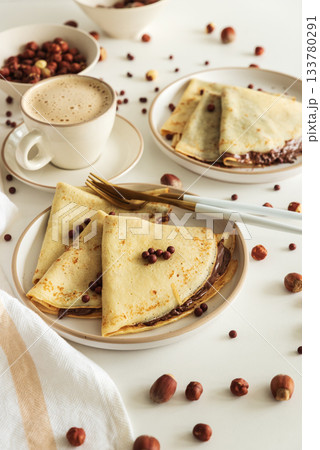 Crepes with chocolate hazelnut spread, strawberries and hazelnuts on a white wooden table. Top view Crepes with chocolate hazelnut spread, strawberries and hazelnuts on a white wooden table. Top view 133780291