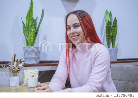 Smiling young woman with red hair in a cozy coffee shop. Smiling young woman with red hair in a cozy coffee shop. 133780485