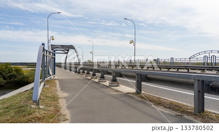 Empty bridge over a river with a paved road in summer. Transportation concept, freight transportation, goods delivery. 133780502