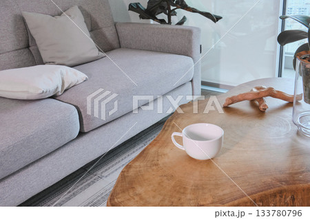 Minimalist living room featuring modern grey sofa and wooden table Minimalist living room featuring modern grey sofa and wooden table 133780796