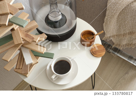 Coffee cup, speaker, and wood decor on side table 133780817