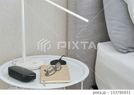 Bedside table with lamp, glasses, and notebook Bedside table with lamp, glasses, and notebook 133780831