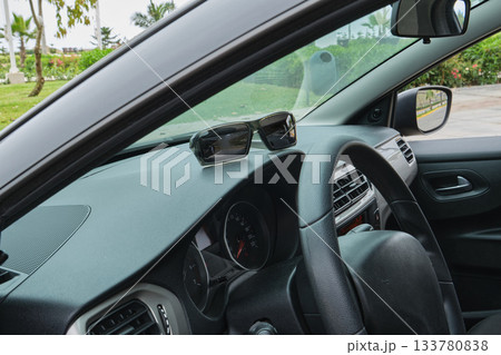 Sunglasses sitting on car dashboard driving on road trip Sunglasses sitting on car dashboard driving on road trip 133780838