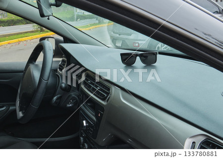 Sunglasses resting on car dashboard during a road trip 133780881