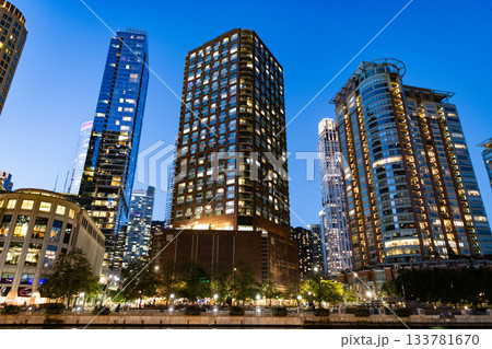 Business skyscraper at night. Skyscraper in city downtown. City architecture. Office building in business district. Modern glass building. Chicago night city. Night cityscape of Chicago skyscraper Business skyscraper at night. Skyscraper in city downtown. City architecture. Office building in business district. Modern glass building. Chicago night city. Night cityscape of Chicago skyscraper 133781670