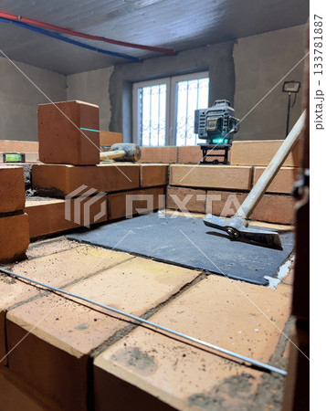 Installation of the cooking plate for a heating stove. Brickwork during the construction of a heating stove. Tools are laid out around. 133781887