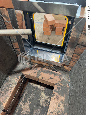Construction of a heating stove. Brickwork of the stove core. The stove door in its frame is installed. The stove core is covered with mineral wool. Close-up. Construction of a heating stove. Brickwork of the stove core. The stove door in its frame is installed. The stove core is covered with mineral wool. Close-up. 133781921
