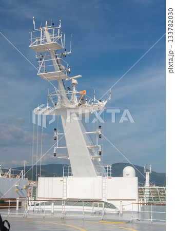 Tall communication mast on a ship, standing against a clear blue sky. Various antennas, sensors and structural elements highlight maritime navigation technology and offshore engineering Tall communication mast on a ship, standing against a clear blue sky. Various antennas, sensors and structural elements highlight maritime navigation technology and offshore engineering 133782030