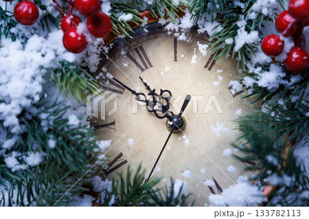 Closeup of holiday clock adorned with holly berries and sparkling decorations for celebrations. 133782113