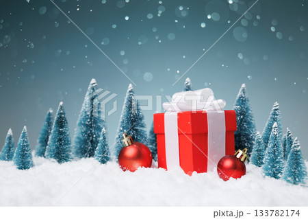 Red gift box on snow with Christmas baubles and miniature trees, copy space Red gift box on snow with Christmas baubles and miniature trees, copy space 133782174