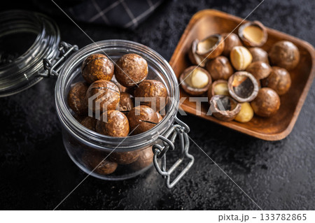 Tasty macadamia nuts in jar on black table. Tasty macadamia nuts in jar on black table. 133782865