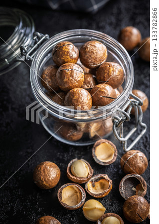Tasty macadamia nuts in jar on black table. Tasty macadamia nuts in jar on black table. 133782866