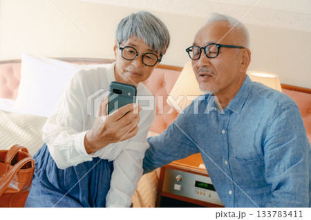 ホテルでスマホを見ながら会話するシニア夫婦 133783411