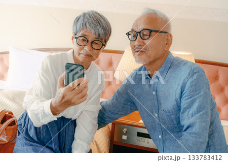 ホテルでスマホを見ながら会話するシニア夫婦 133783412