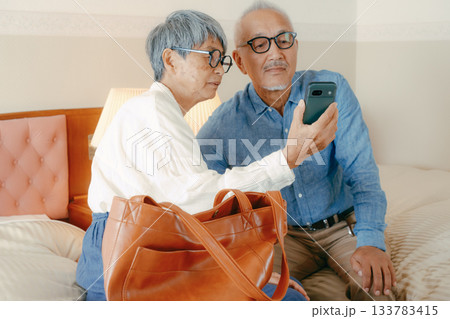 ホテルでスマホを見ながら会話するシニア夫婦 ホテルでスマホを見ながら会話するシニア夫婦 133783415