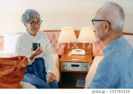 ホテルでスマホを見ながら会話するシニア夫婦 133783419