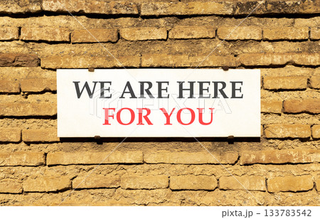 Support, help and we are here for you symbol. Concept words We are here for you on beautiful white marble sign plate. Beautiful brick wall background. Business we are here for you concept. Copy space. 133783542