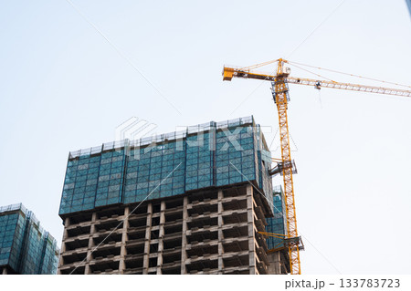 High rise construction site with yellow tower crane and unfinished concrete structure 133783723