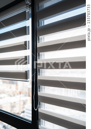 Zebra roller blinds on tall window with sunlight and urban city view background Zebra roller blinds on tall window with sunlight and urban city view background 133783733