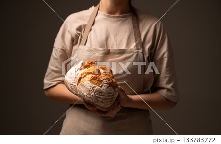 Artisan baker presenting rustic handmade bread loaf, showcasing traditional craftsmanship and natural quality 133783772