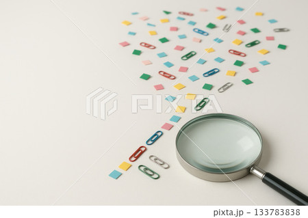 Magnifying glass next to multi-colored stationery scattered on the table. Space for text. Magnifying glass next to multi-colored stationery scattered on the table. Space for text. 133783838