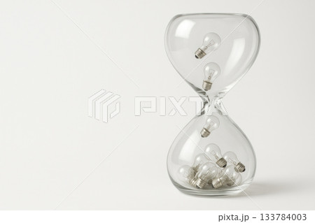 An hourglass with falling light bulbs. Space for text. An hourglass with falling light bulbs. Space for text. 133784003