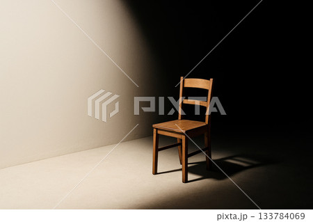A lonely wooden chair in a beam of light. Space for text. 133784069