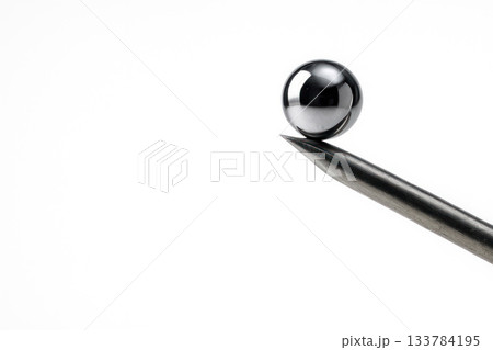 A metal ball balancing on the tip of a needle. Space for text. 133784195