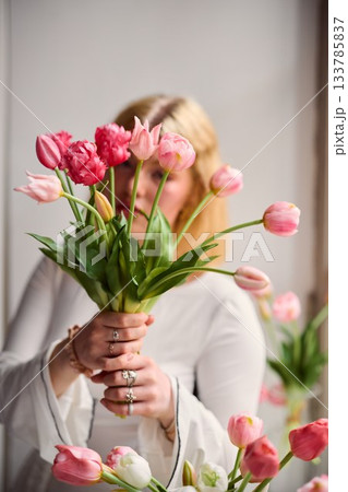 Bright studio scene with woman preparing floral bouquet Bright studio scene with woman preparing floral bouquet 133785837