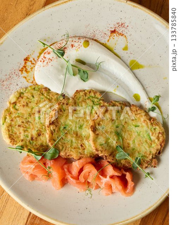 Beautifully plated savory zucchini bites, Refined bistrostyle dish featuring golden zucchini and salmon Beautifully plated savory zucchini bites, Refined bistrostyle dish featuring golden zucchini and salmon 133785840