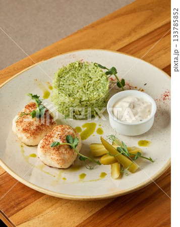 Exquisite seafood display featuring expertly cooked scallops paired with fragrant rice and vibrant garnishes 133785852