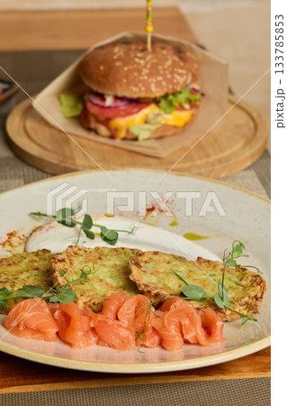 Sophisticated food display showcasing sesame bun burger with assorted fresh accompaniments Sophisticated food display showcasing sesame bun burger with assorted fresh accompaniments 133785853