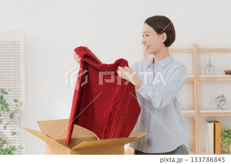 箱からセーターを出す女性 133786845