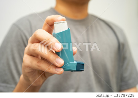 Asthma and chronic obstructive pulmonary disease COPD, Asian young man using metered dose inhaler MDI. 133787229