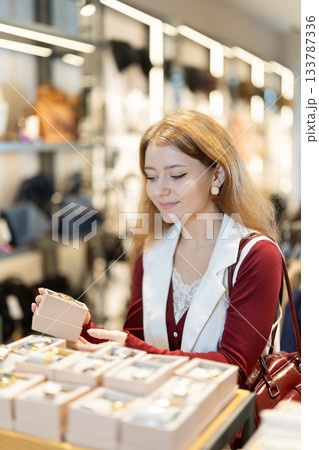Positive young girl choosing wrist watch in accessories store Positive young girl choosing wrist watch in accessories store 133787336